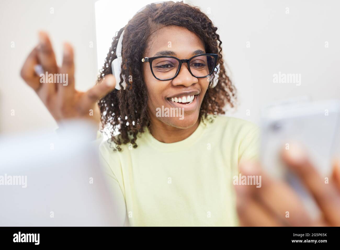 Donna di affari afro-americana come freelancer durante la videochat con lo smartphone nell'ufficio domestico Foto Stock