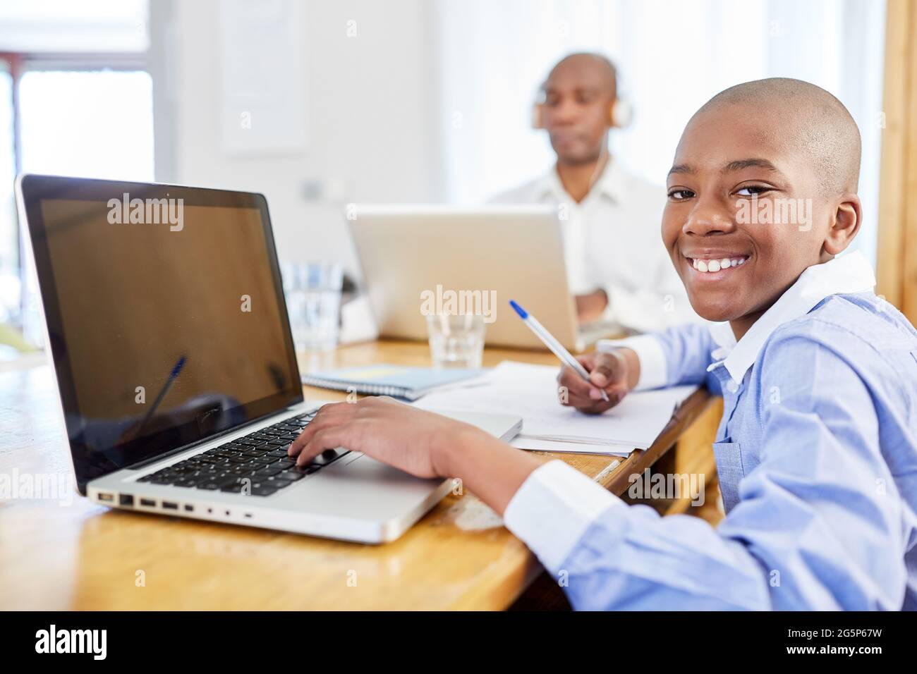 Studente afroamericano che usa il computer portatile durante l'apprendimento a distanza a casa come ufficio domestico Foto Stock