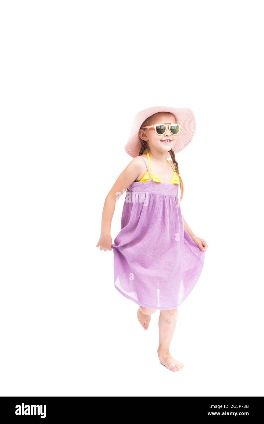 Verticale full length studio ritratto di carina ragazza caucasica che indossa abiti estivi, occhiali da sole e cappello in posa su fotocamera, sfondo bianco Foto Stock