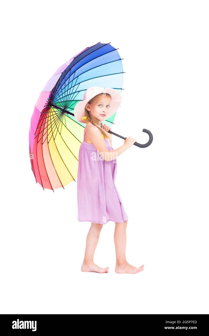 Verticale full length studio ritratto di carina ragazza caucasica che indossa abiti estivi e cappello che tiene ombrello colorato in posa sulla macchina fotografica, sfondo bianco Foto Stock