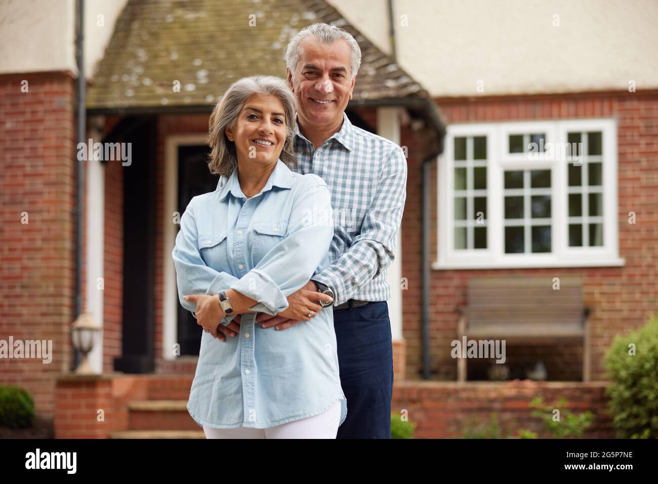 Ritratto di Coppia Matura in piedi nel giardino davanti a casa da sogno in campagna Foto Stock