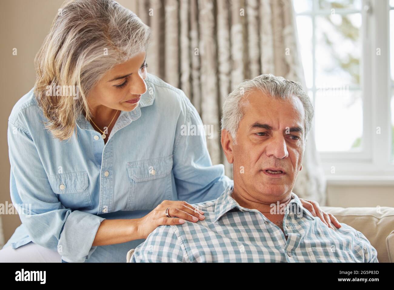 Donna matura consolante l uomo con la depressione a casa Foto Stock