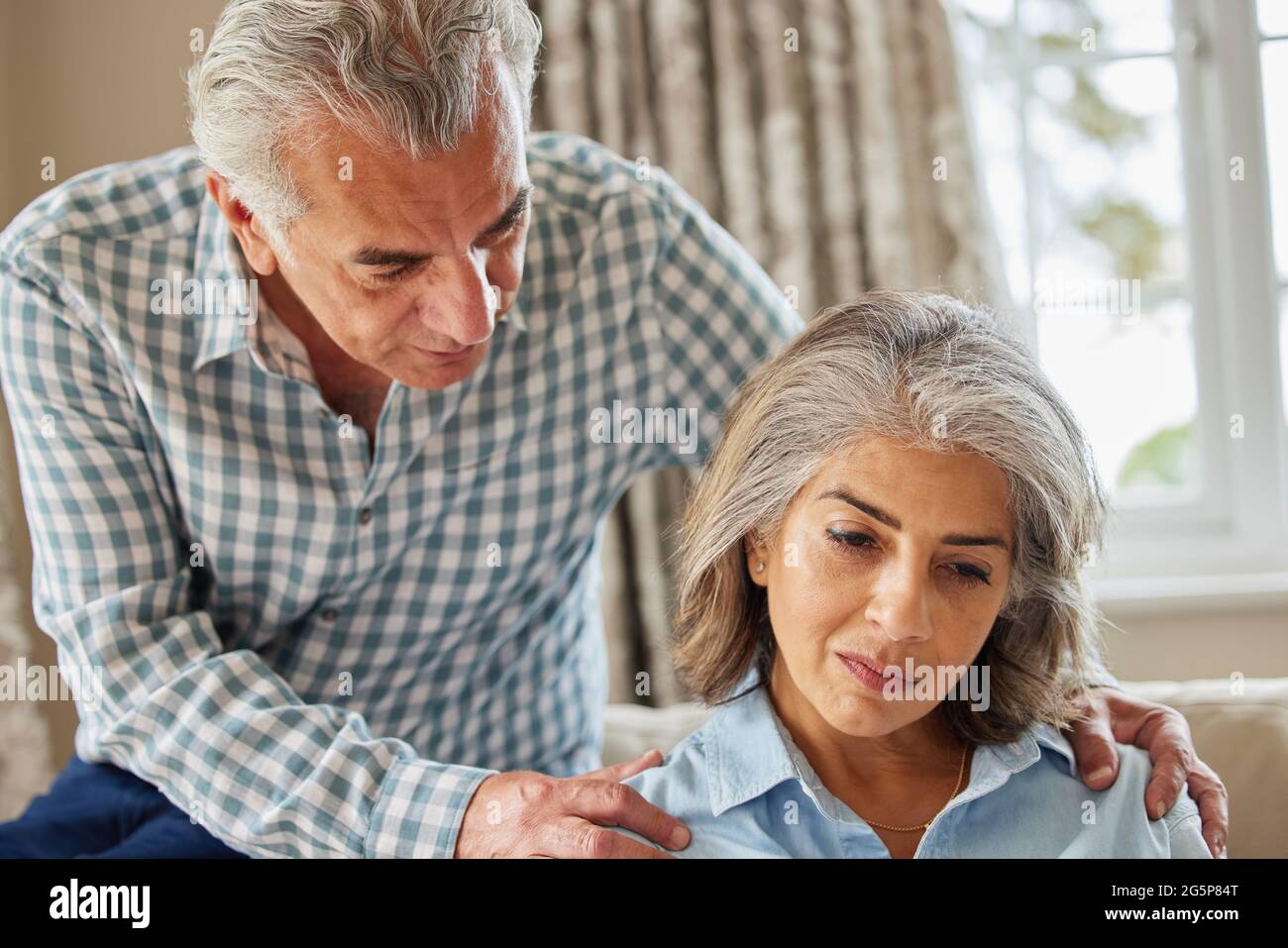 Uomo maturo consolante donna con depressione a casa Foto Stock