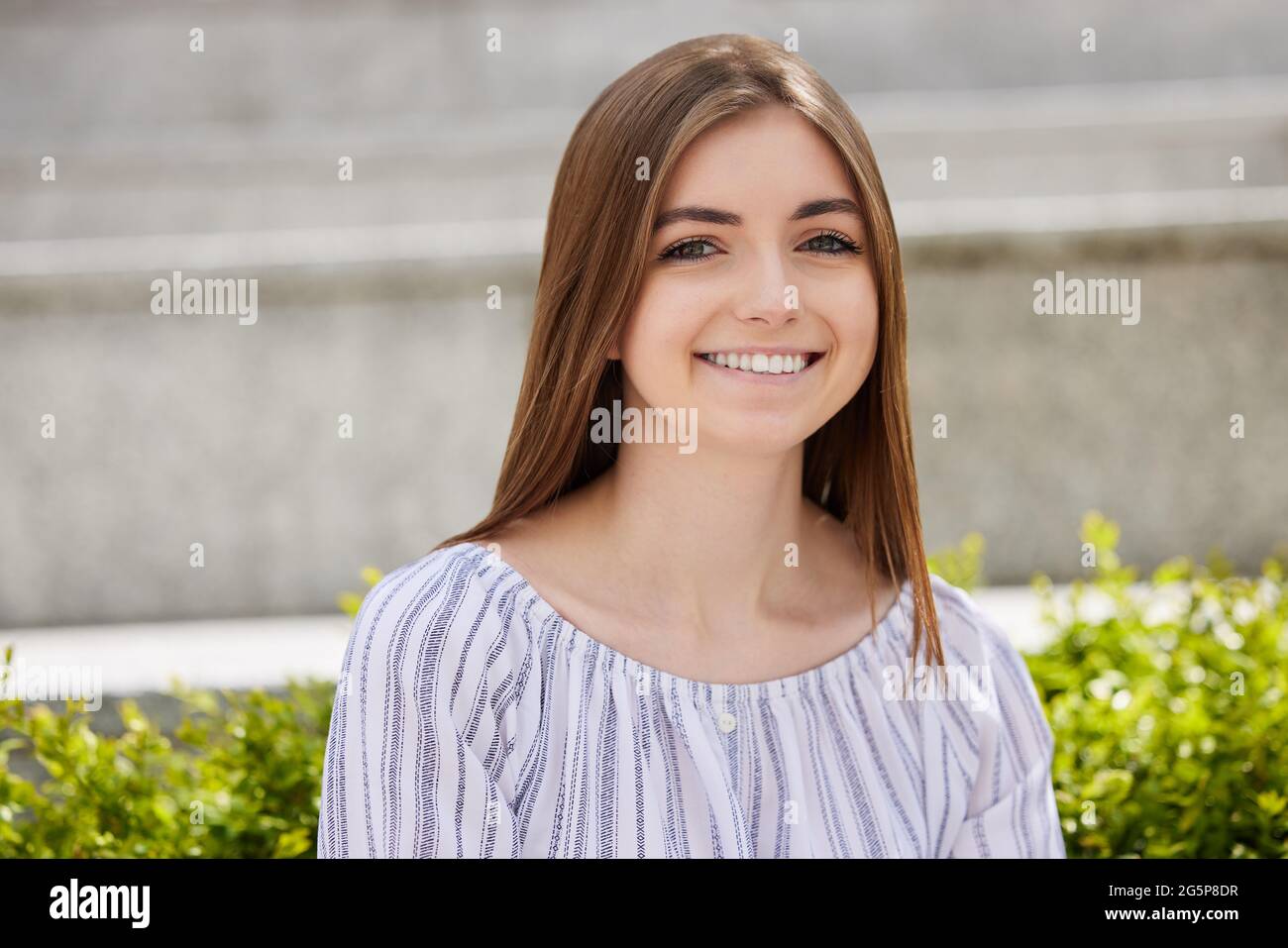 Ritratto di una giovane studentessa sorridente seduta all'esterno del College Campus Foto Stock