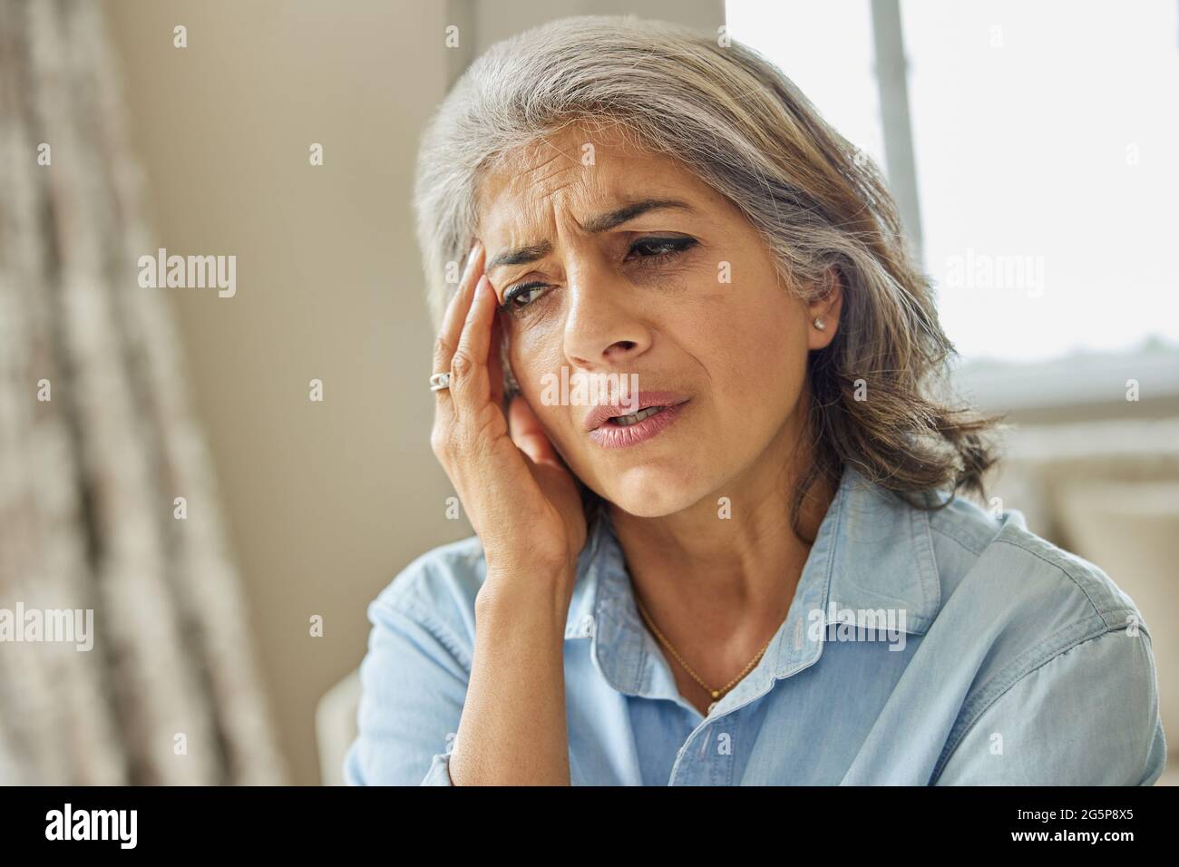 Donna matura a casa che soffre di mal di testa o perdita di memoria Foto Stock