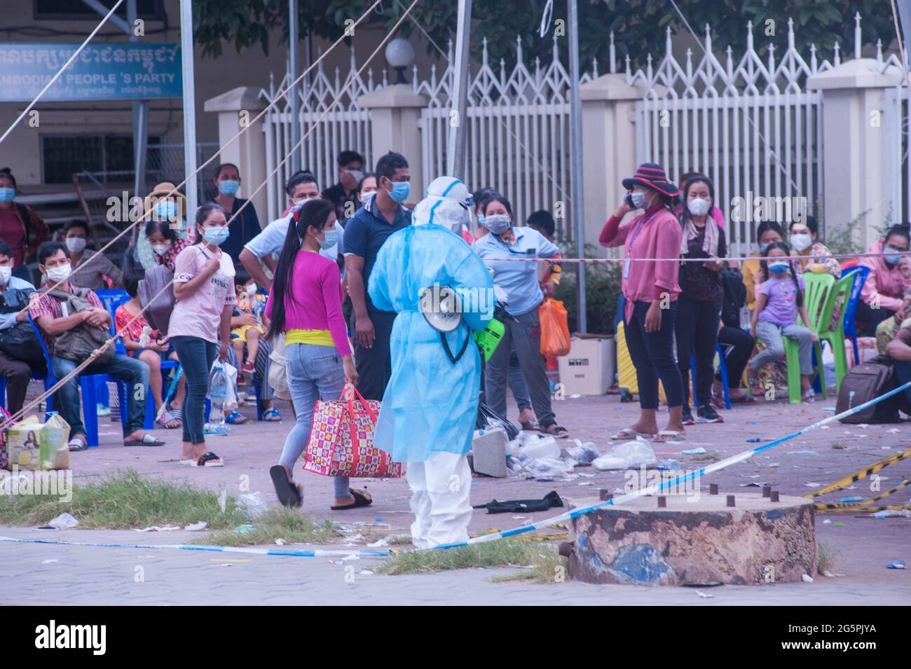 Phnom Penh, Cambogia. 29 giugno 2021. Per 4 mesi Phnom Penh ha combattuto contro un picco COVID - 19. Un EMT in DPI completo dirige un sito di test di massa. Un gruppo di cambogiani che hanno tutti provato il virus sono in attesa di essere prelevati dalle ambulanze. Credito: Kraig Lieb / Alamy Live News Foto Stock