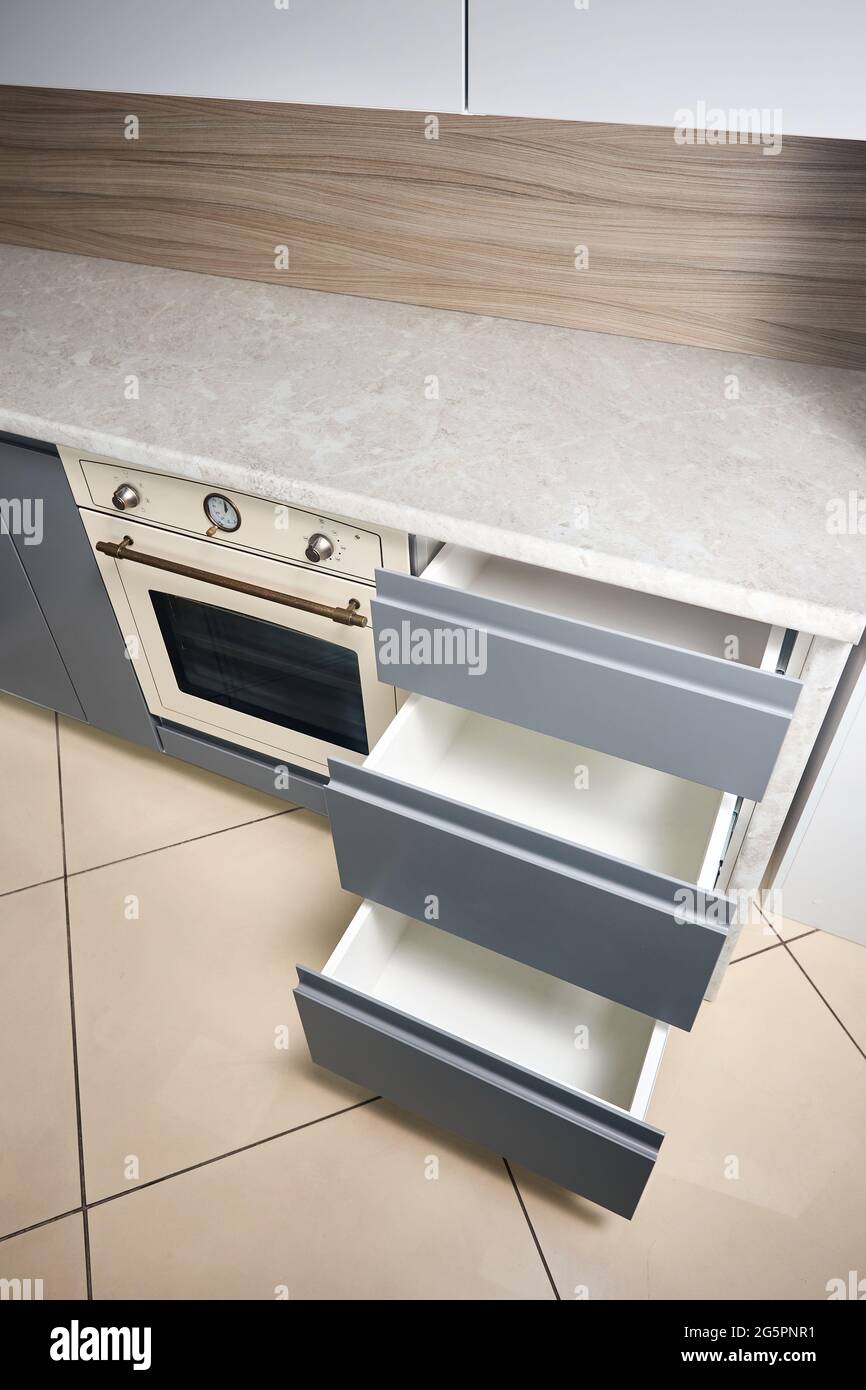 Soluzione per posizionare utensili da cucina in una cucina moderna. Scaffali con cassetti estraibili orizzontali in armadio per utensili da cucina sotto porcellana Foto Stock