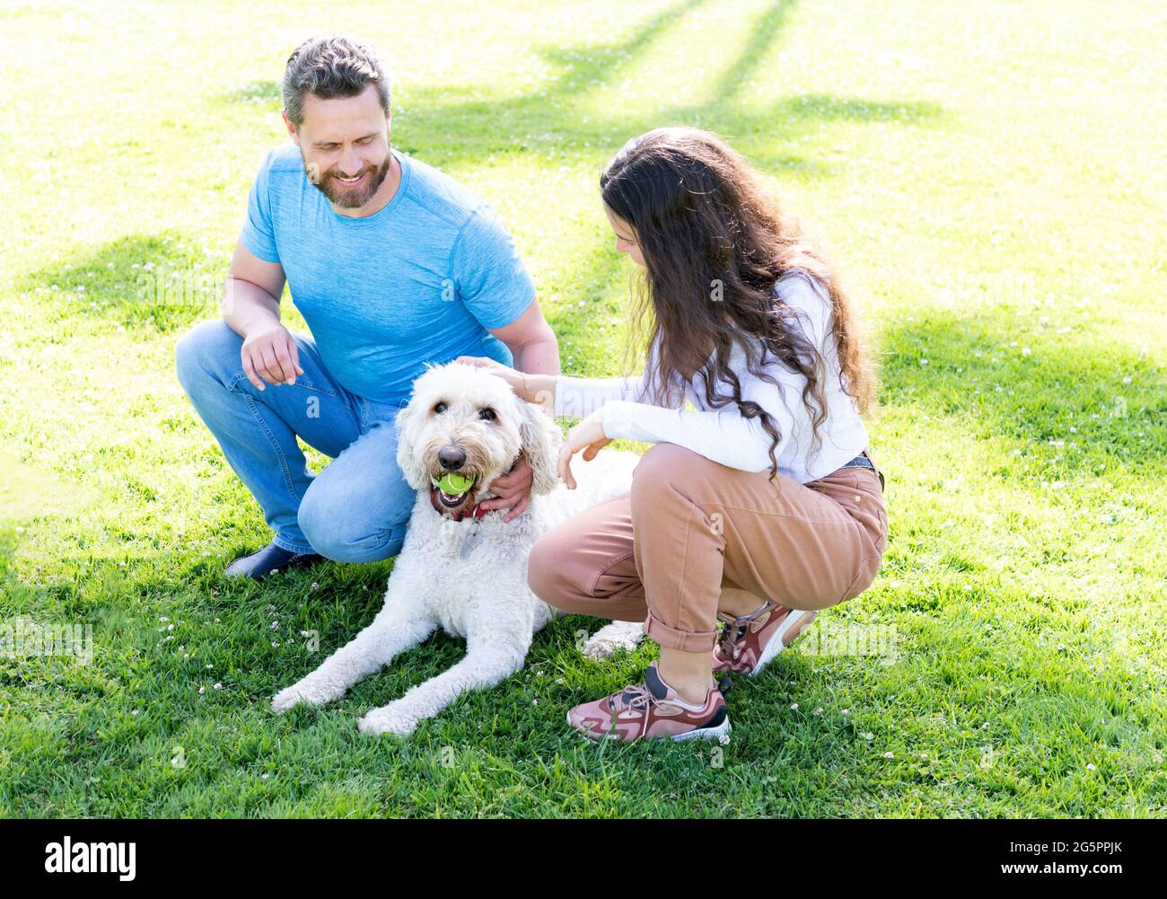 giovane famiglia di uomo e donna gioca con cane animale domestico in parco su erba verde, amante degli animali domestici Foto Stock