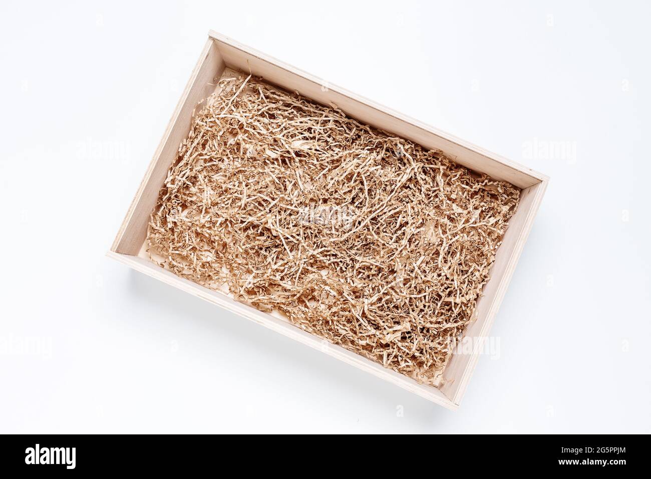 Scatola di legno regalo aperta con riempitivo di carta trinciata su sfondo bianco per il posizionamento del prodotto. Vista dall'alto, mockup Foto Stock