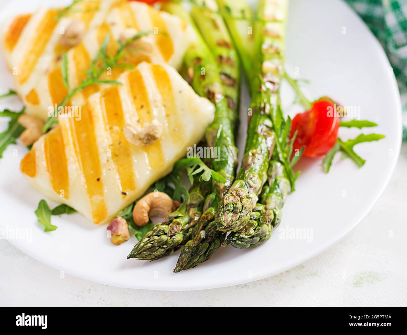 Insalata di formaggio halloumi alla griglia con pomodori e asparagi sul piatto su sfondo chiaro. Cibo vegetariano sano. Foto Stock