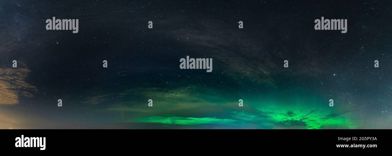 Foto panoramica vera e propria della bella aurora boreale morbida - luci verdi luminose su cielo notturno nero con alcune nuvole. Un sacco di stelle reali visto nel Nord Foto Stock