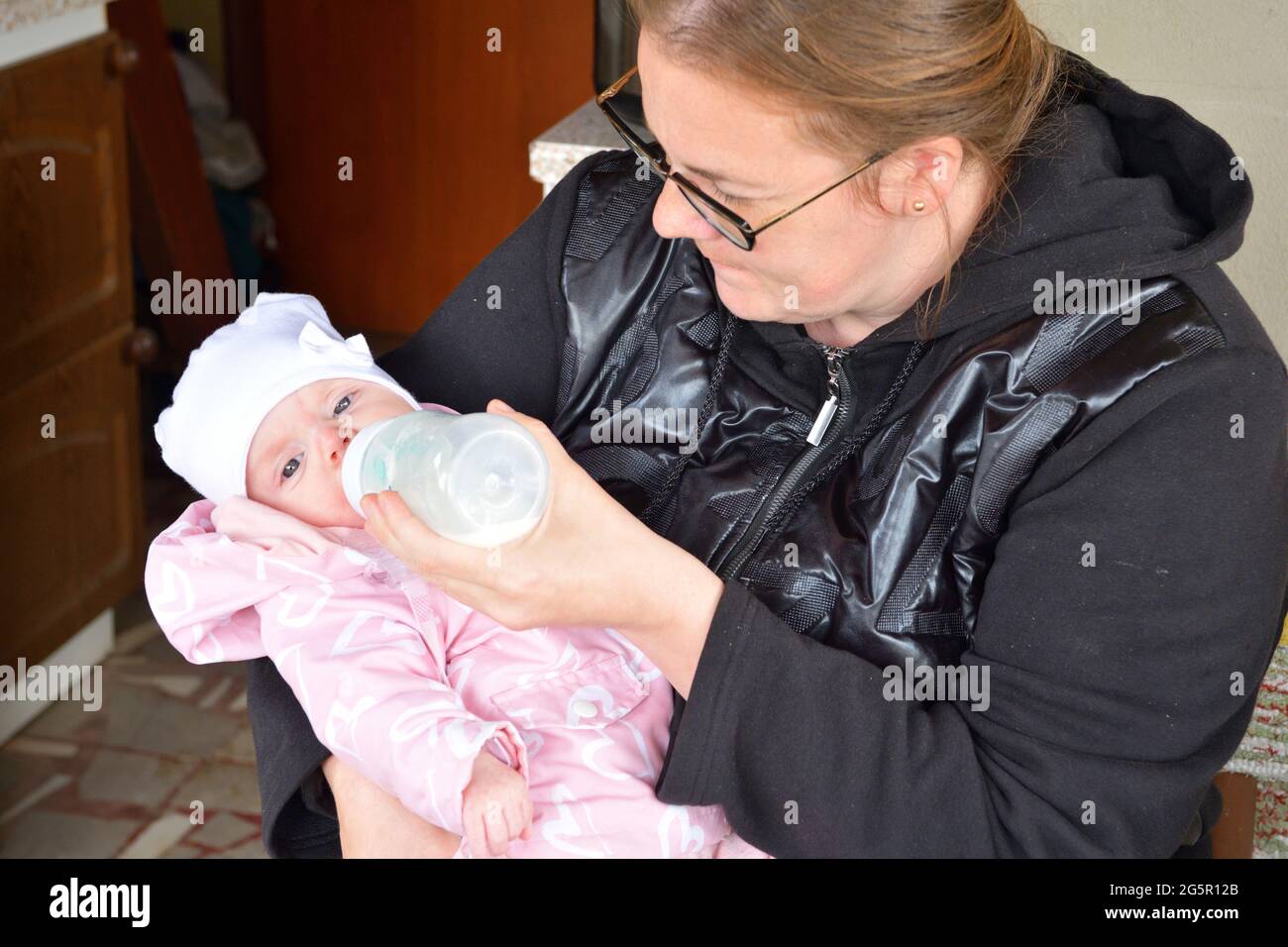 Una madre nutre il suo bambino con il latte da un biberon Foto Stock