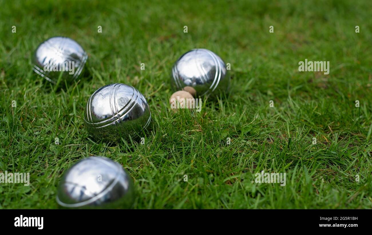 Primo piano di palline di petanque in acciaio su un prato verde. Sfere di petanque in acciaio cromato giacciono sull'erba. Gioca nel tuo giardino. Foto Stock