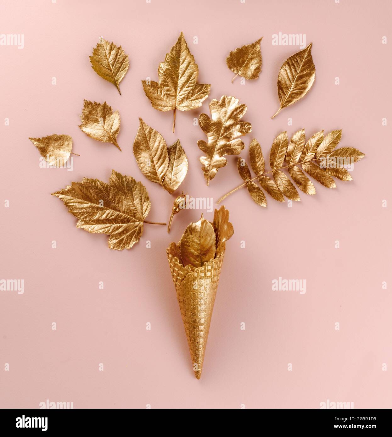 Art. Parete Set botanico. Decorazione stile di vita. Cono gelato in oro con foglie d'oro autunnali, su sfondo rosa. Disposizione piatta. Vista dall'alto. Bella composizione Foto Stock
