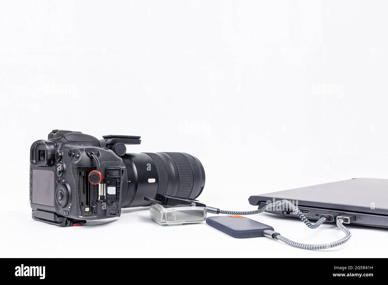 workstation di elaborazione fotografica con un computer portatile, una dslr, un lettore di schede cf e un'unità disco ssd su sfondo bianco con spazio per la copia Foto Stock