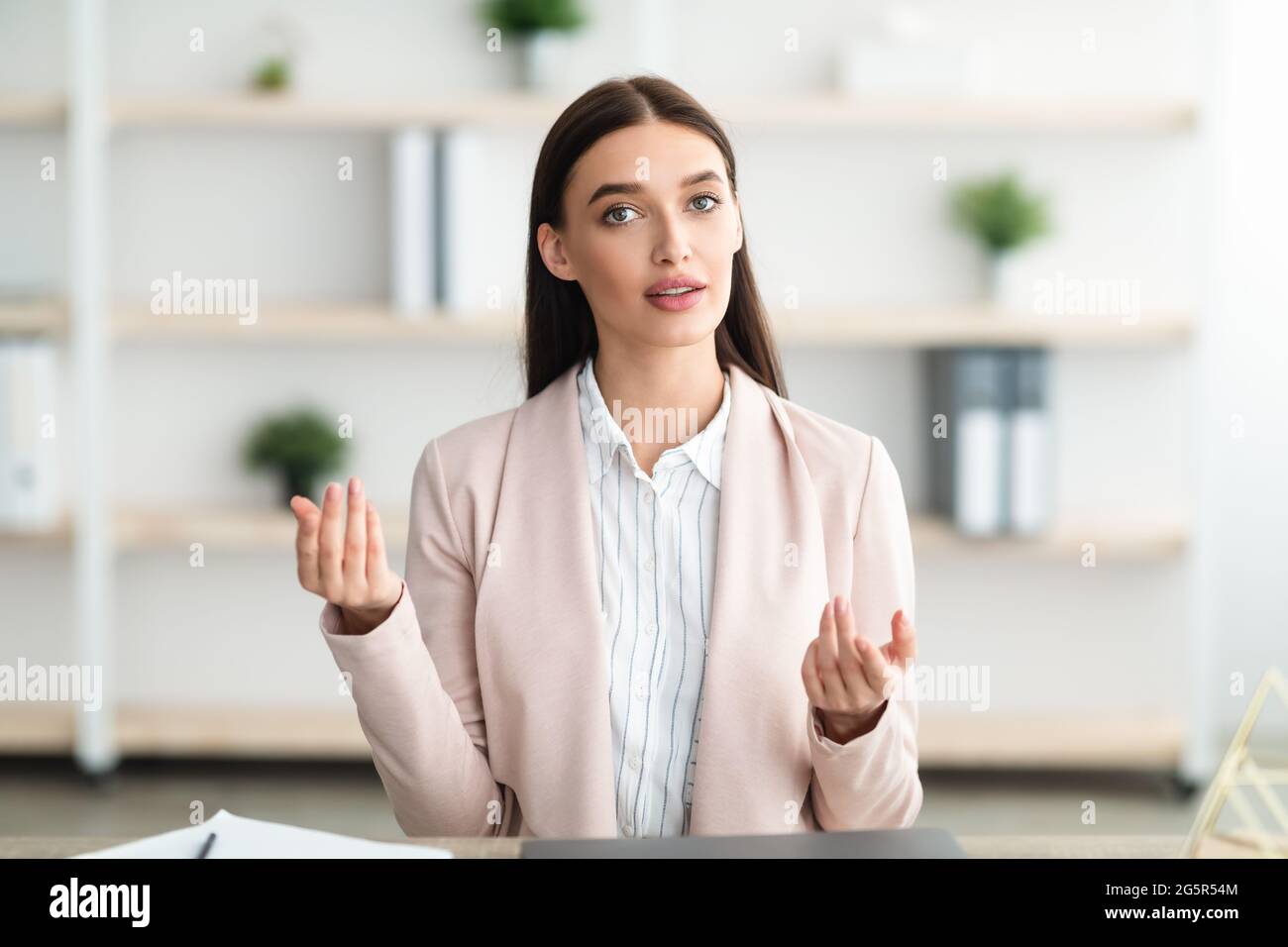 Giovane Businesswoman che parla con Camera Consulting seduto in ufficio moderno Foto Stock