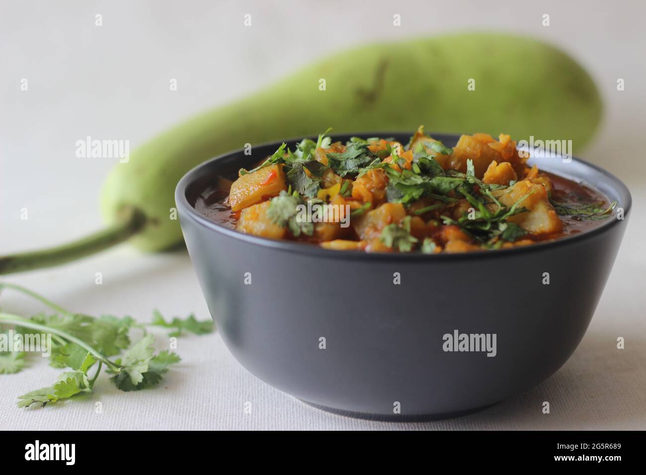 Bottiglia di curry Gourd con lenticchie. Una pentola di lenticchie di ceci cotte con una bottiglia di cipolle di zucca pomodori e spezie. Scatto su sfondo bianco. Foto Stock