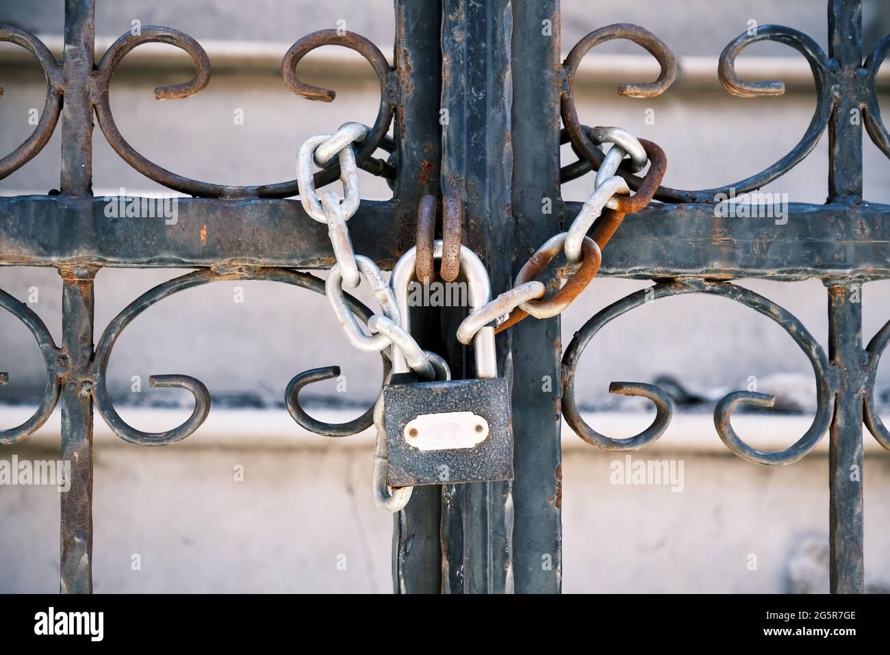 Cancello in ferro battuto chiuso con una catena arrugginita e lucchetto  Foto stock - Alamy