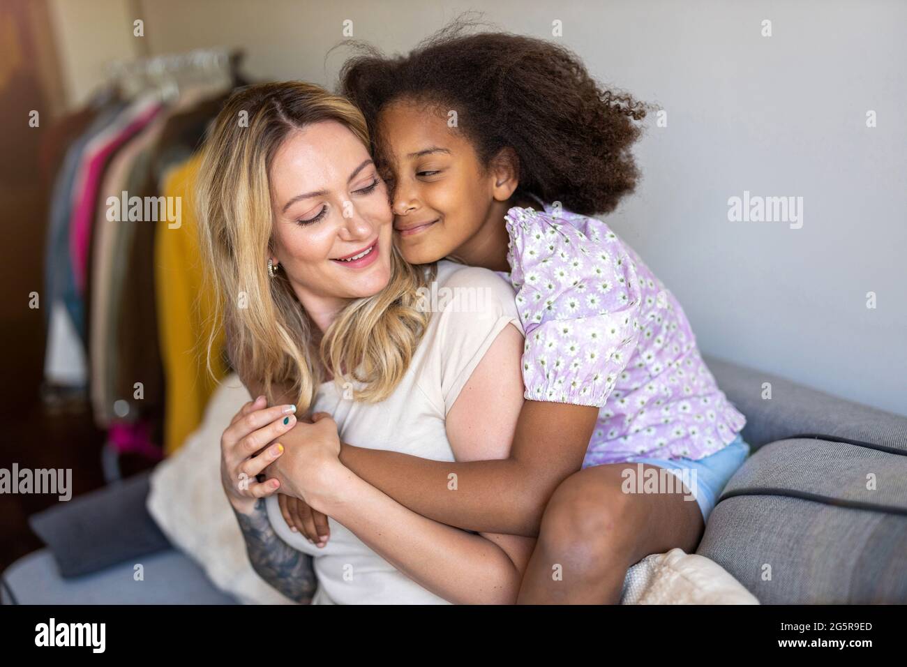 Madre e figlia abbracciano a casa Foto Stock