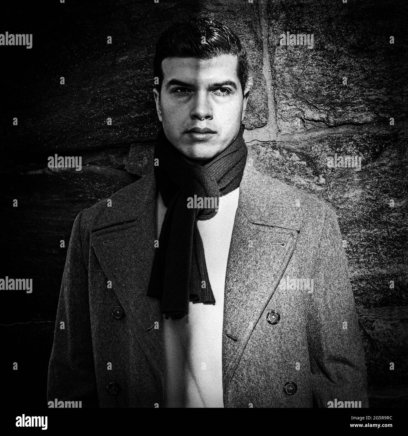 Un giovane bell'uomo si trova al confine tra buio e luminoso, nero e bianco, ombra e sole, un concetto di complessità della realtà A. Foto Stock