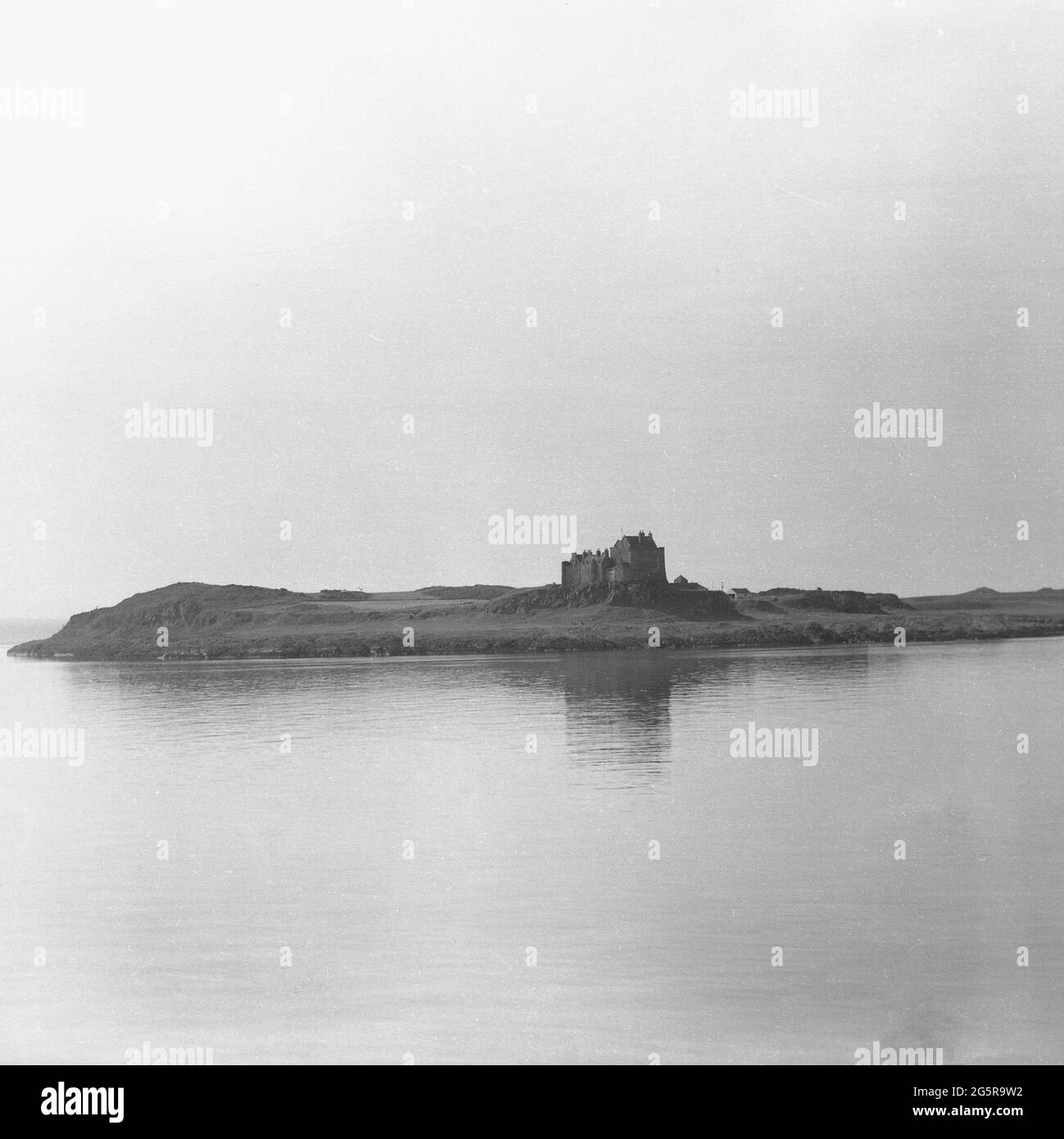 1950s, vista storica delle rovine su un pezzo di terreno a basso livello accanto alle calme acque di un lago, Sottish Highlands, Scozia, Regno Unito. Foto Stock