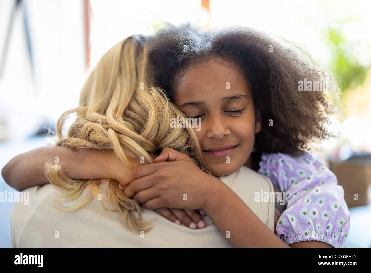 Madre e figlia abbracciano a casa Foto Stock