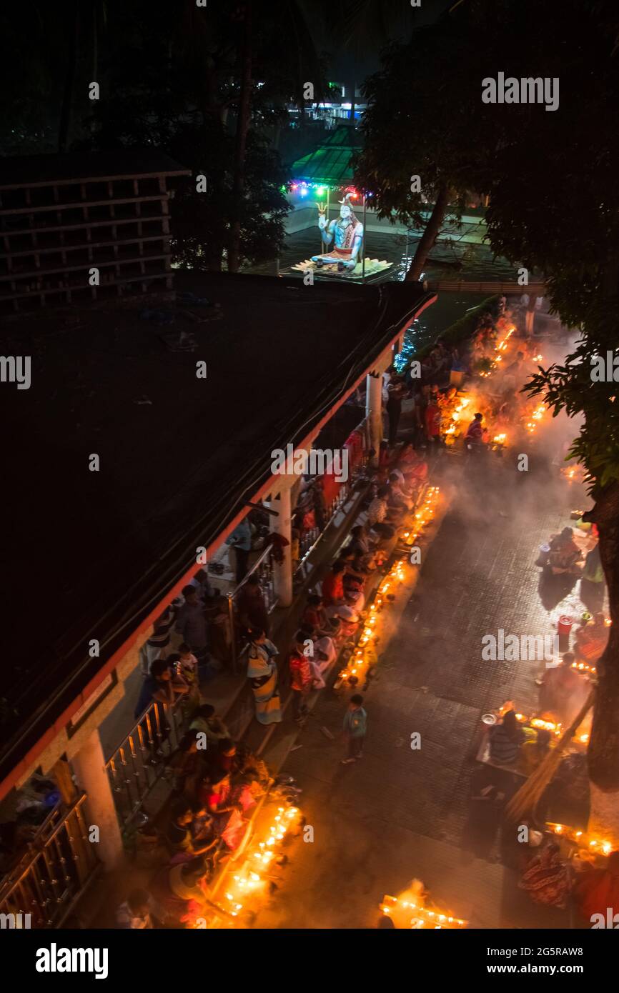 Migliaia di devoti indù si siedono con la candela (Prodip) per pregare Dio di fronte al tempio Shri Shri Lokanath Brahmachari Ashram durante i religiosi Foto Stock