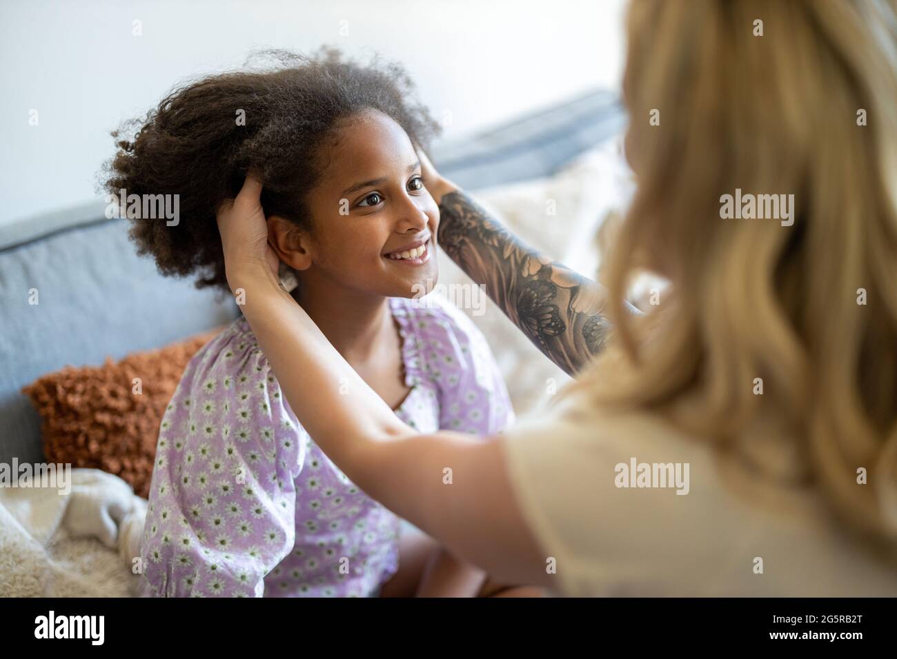 Madre che piega i capelli della figlia a casa Foto Stock