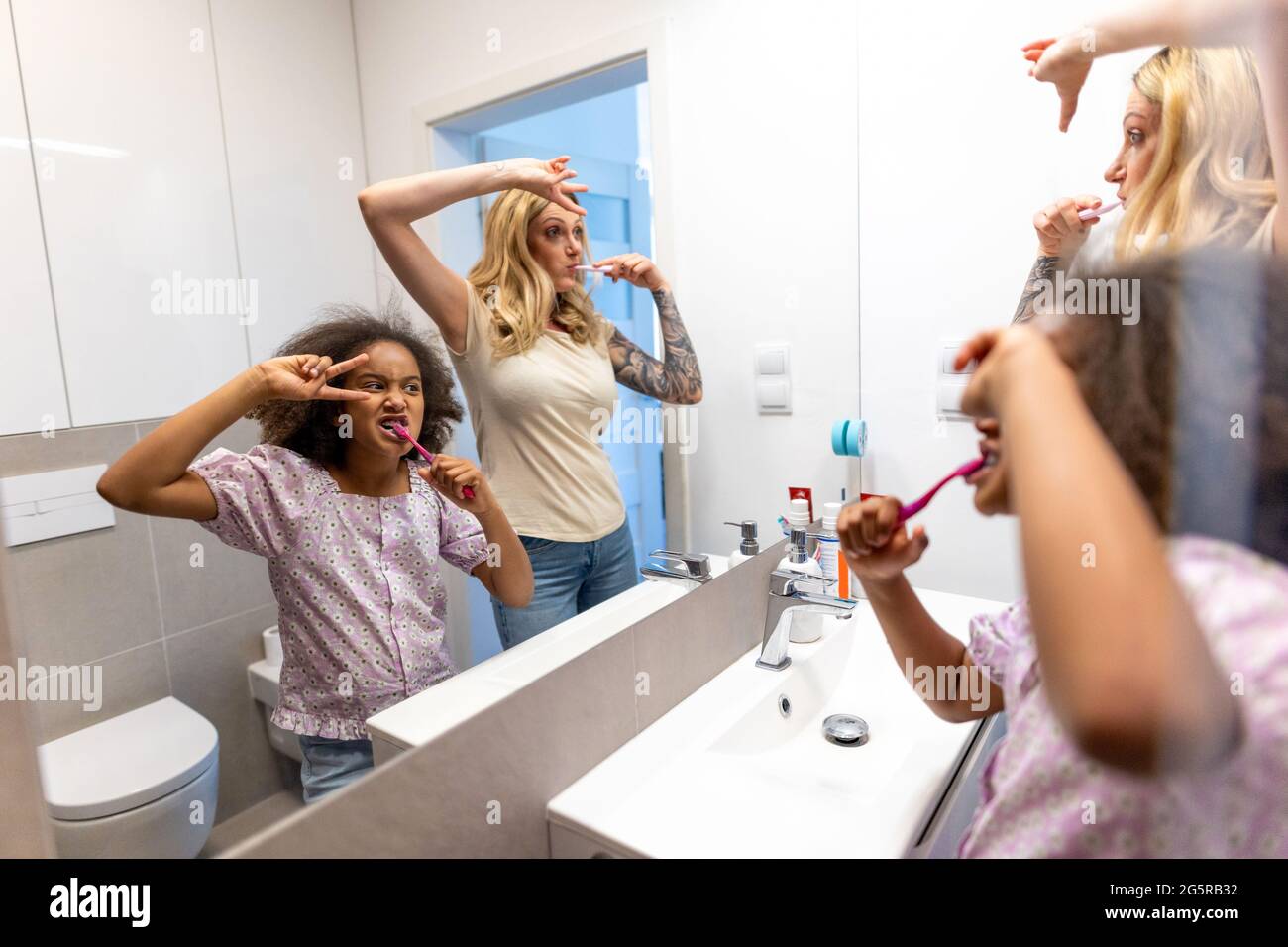 Madre e figlia che spazzolano i denti al mattino Foto Stock