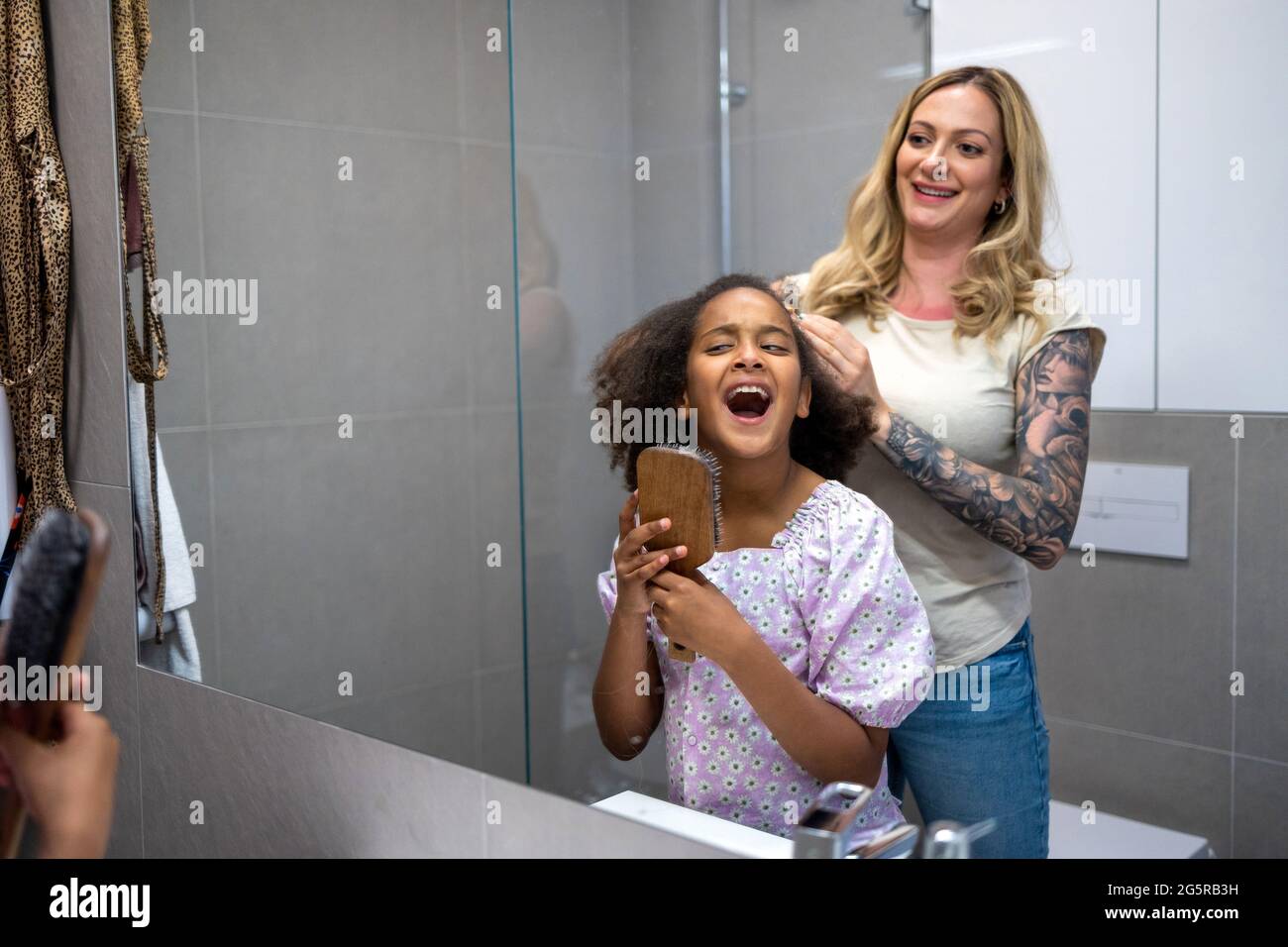 Madre che piega i capelli della figlia a casa Foto Stock