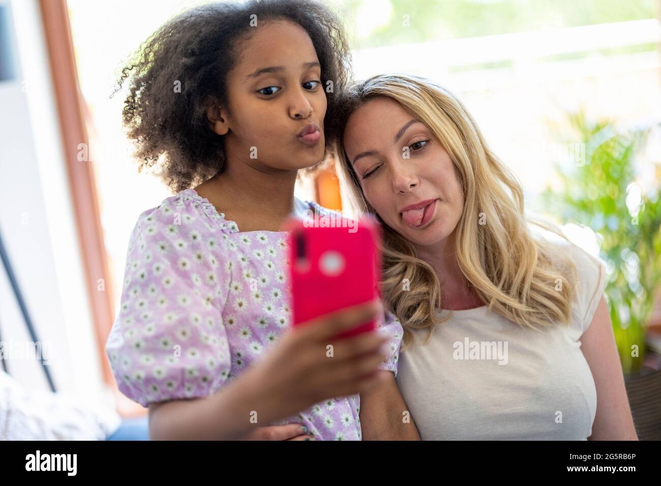 Madre e sua giovane figlia che prendono un selfie a casa Foto Stock