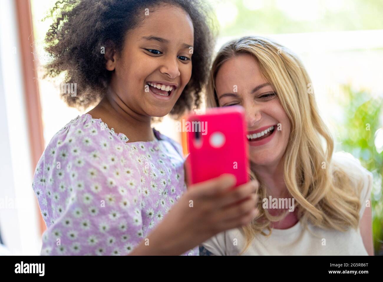 Madre e sua giovane figlia che prendono un selfie a casa Foto Stock