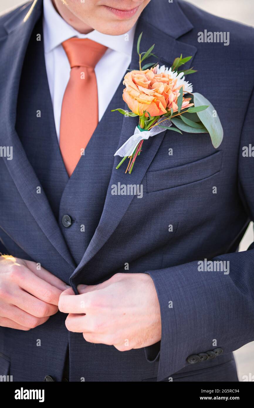 Cappotto a bottone giovane uomo caucasico ornato con boutonniere arancione Foto Stock