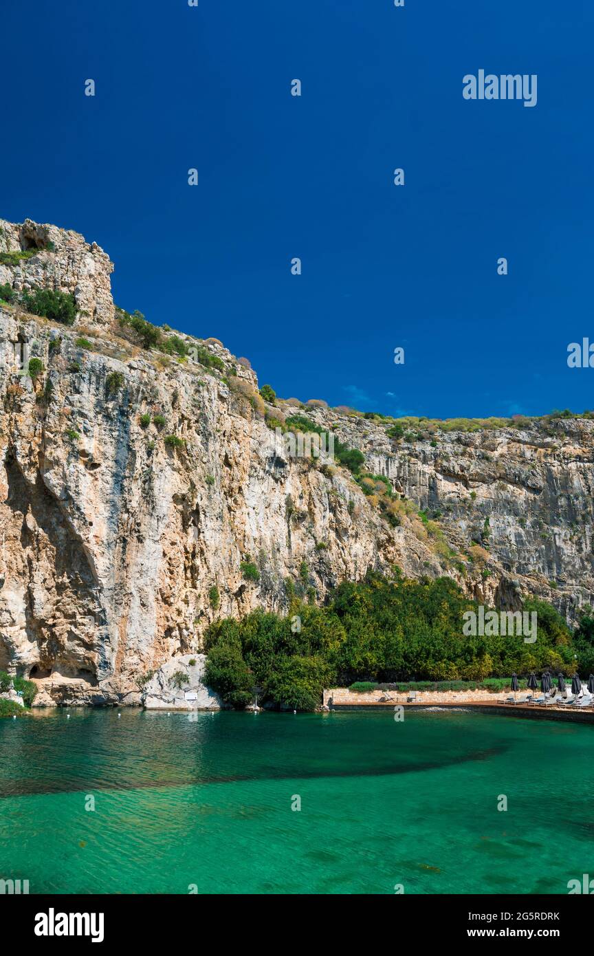 Lago Vouliagmeni in Grecia nella soleggiata giornata estiva. Piccolo lago di acqua salmastra alimentato. Paesaggio panoramico di montagna bianca e acqua verde. Molla termica. CENTRO BENESSERE Foto Stock