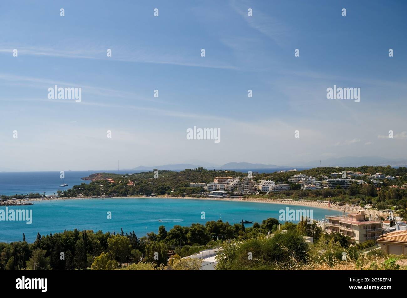 Paesaggio urbano della riva del mare in Grecia. Vista dall'alto. Architettura urbana e molti alberi verdi. Zona collinare. Giorno di sole. Mar Egeo. Foto Stock
