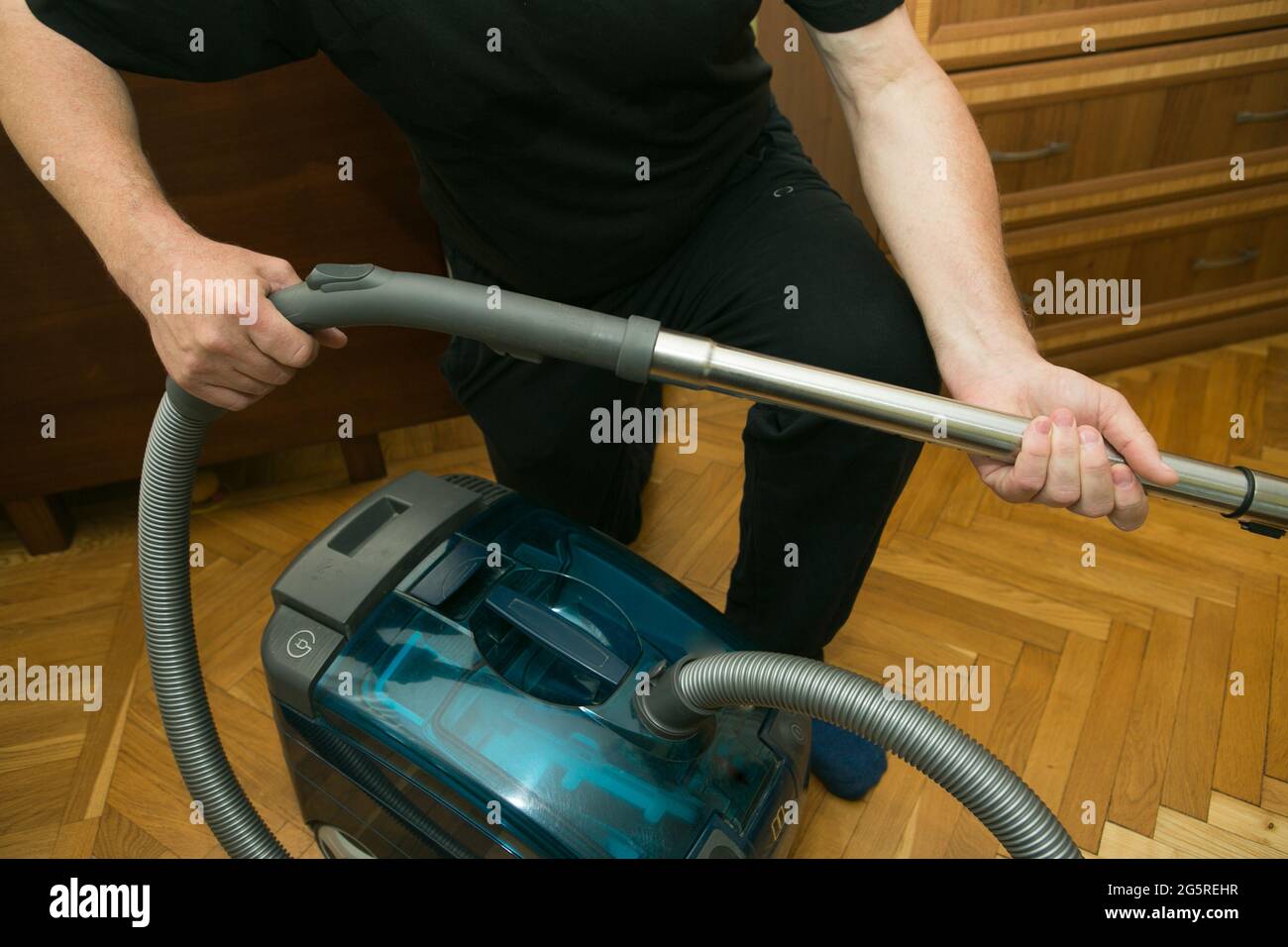 Il processo di pulizia di una stanza con un aspirapolvere con un aquafiltro. Mani di un uomo che prepara l'aspirapolvere per il lavoro. Montaggio del vuoto c Foto Stock