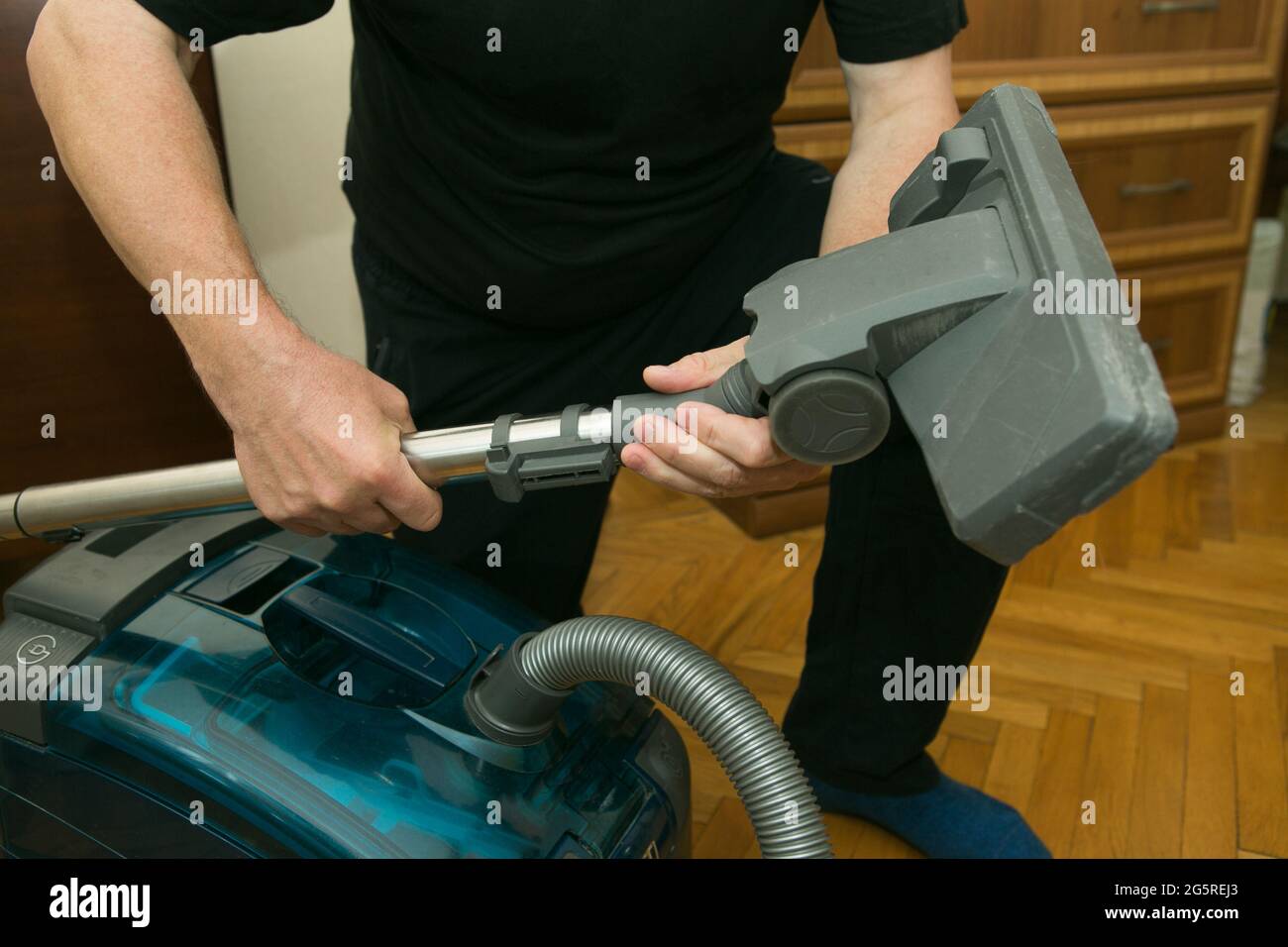 Il processo di pulizia di una stanza con un aspirapolvere con un aquafiltro. Mani di un uomo che prepara l'aspirapolvere per il lavoro. Montaggio del vuoto c Foto Stock