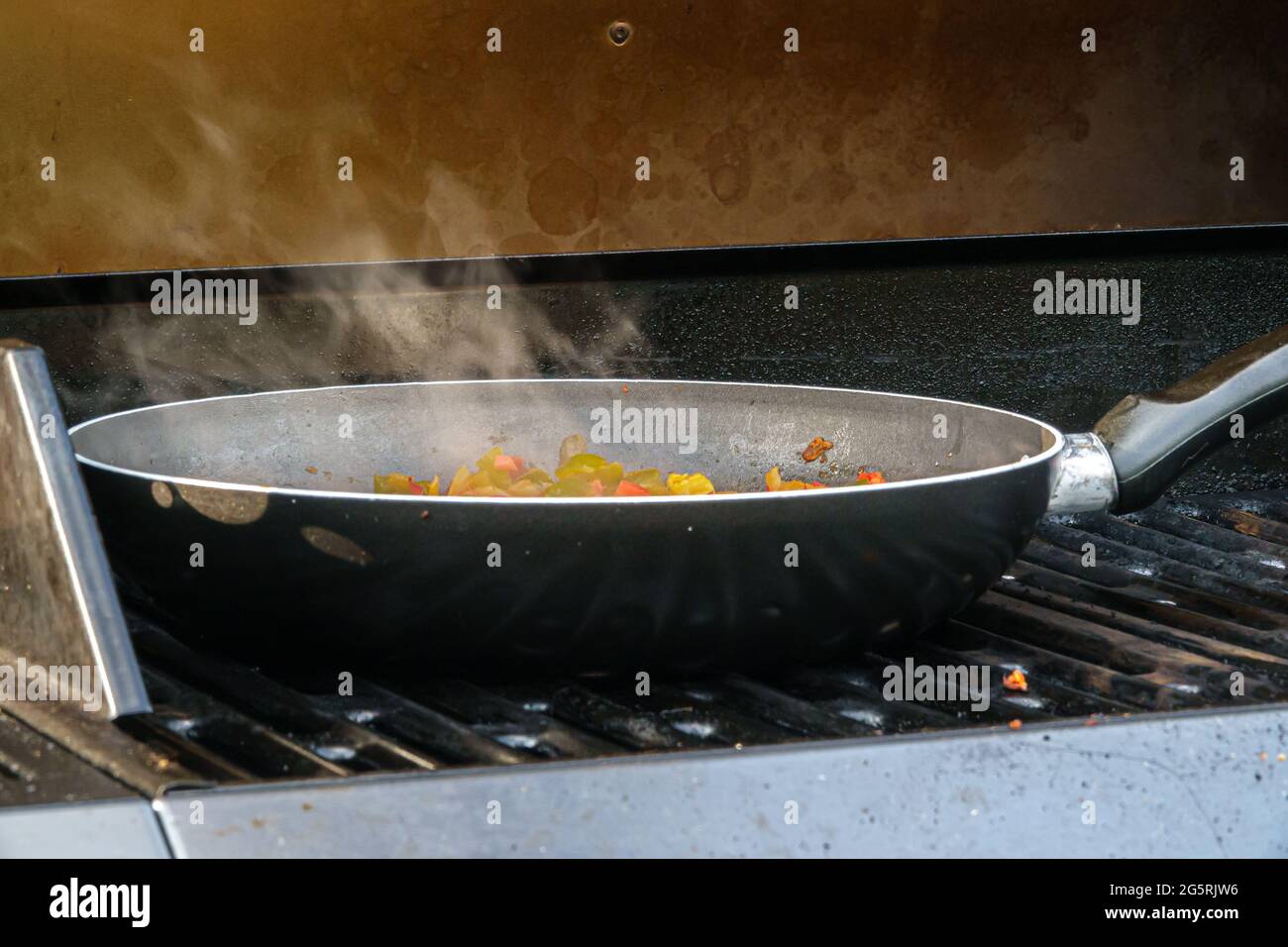 Vapore che si alza dalla padella di verdure che cucinano all'aperto su una griglia barbecue Foto Stock