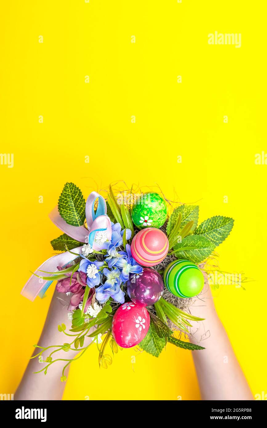 Bouquet di Pasqua, cartolina per la stampa, bouquet regalo in un secchio per Pasqua. La mano dei bambini crea un bouquet decorativo su sfondo giallo Foto Stock