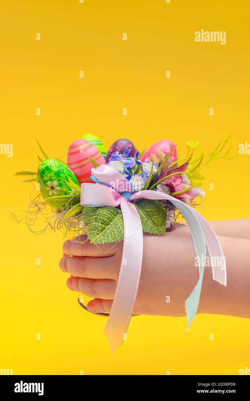 Cartolina di Pasqua. Bouquet decorativo per Pasqua nelle mani di un bambino. La mano dei bambini tiene un bouquet su uno sfondo giallo. Posiziona per il testo Foto Stock