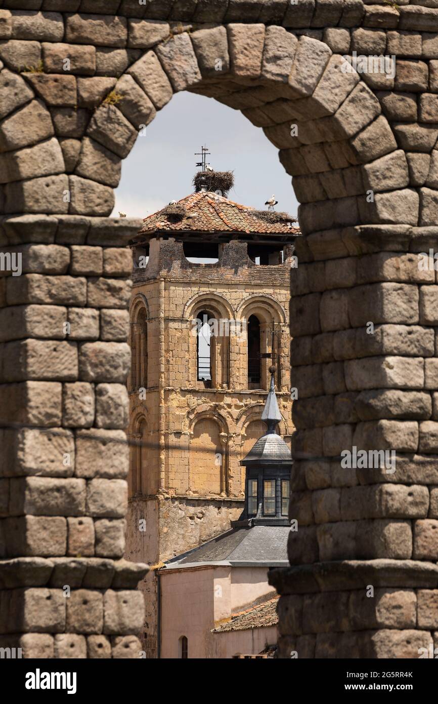 Campanile e nidi cicogna della chiesa Santos Justo y Pastor, attraverso un arco dell'Acquedotto di Segovia Foto Stock