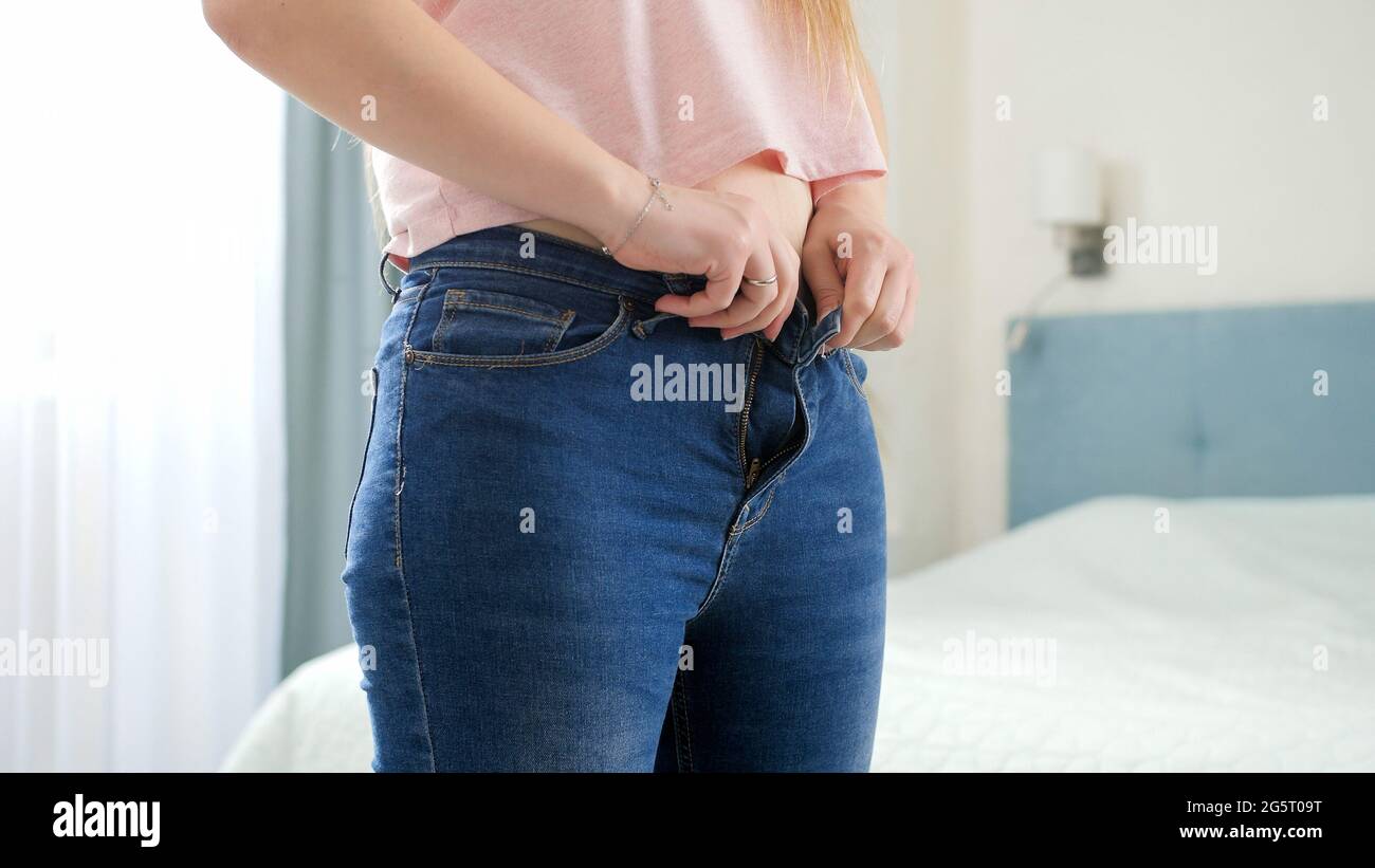 Giovane donna con fianchi larghi e pancia che si mette su jeans stretti e  che lotta per buttarli. Concetto di peso eccessivo, obese femmina, dieta e  Foto stock - Alamy