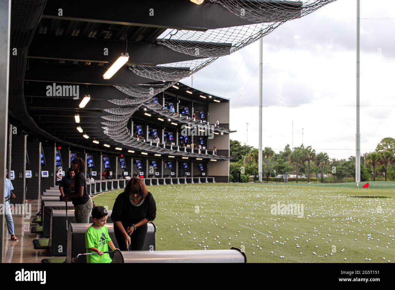 Vista di giorno delle persone che giocano al TopGolf Entertainment Building a Miami, Florida. Madre e bambino che gioca a golf. Foto Stock