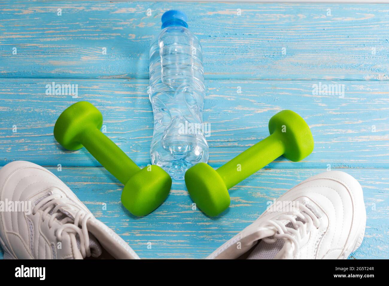 scarpe da running con manubri e una bottiglia d'acqua su sfondo di legno. Stile di vita sano. Foto Stock