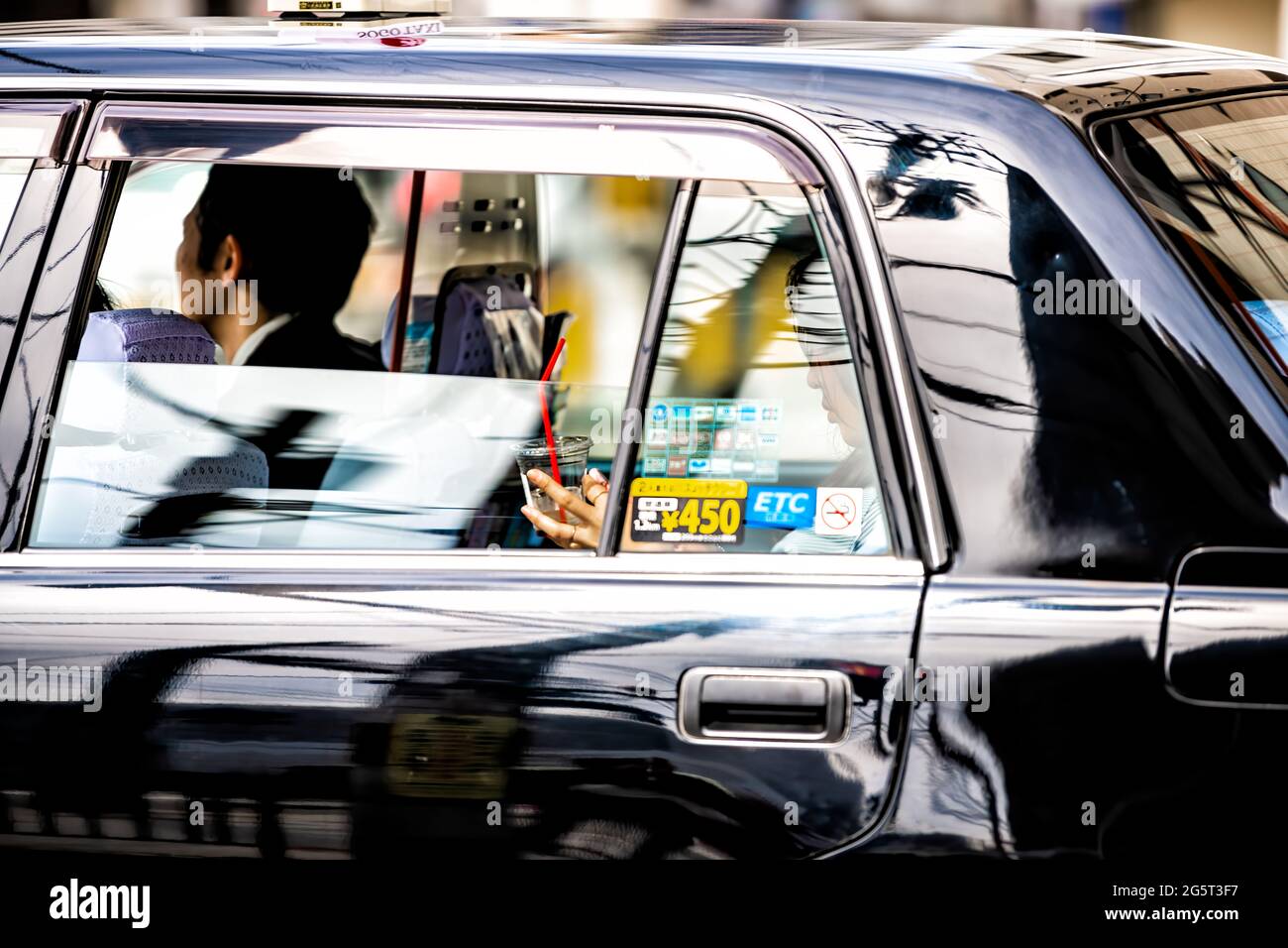 Kyoto, Giappone - 17 aprile 2019: Traffico stradale del centro con giovane donna locale ragazza che cavalcano all'interno nero taxi cabina closeup testando usando il telefono Foto Stock