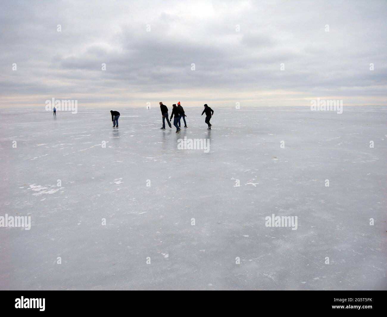 Pattinatori di ghiaccio sul lago ghiacciato, cielo nuvoloso, Paesi Bassi, Ijsselmeer Foto Stock