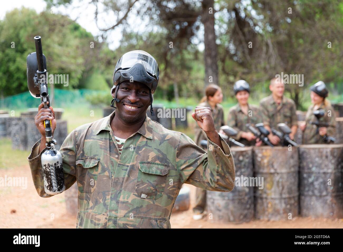 Ritratto di paintball giocatore in camouflage e maschera protettiva in piedi con pistola dopo paintball match Foto Stock