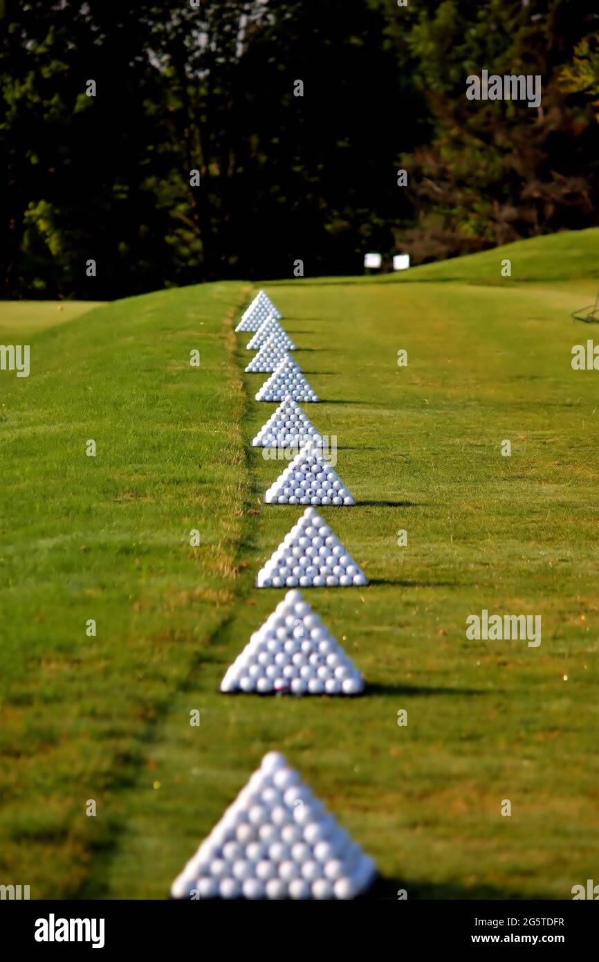 Palline da golf accatastate in piramidi pronte per il tempo di pratica Foto Stock