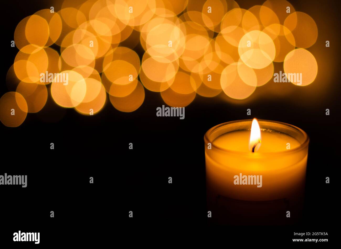 Candela aromatica con fiamma e bokeh di forma rotonda su sfondo scuro per ringraziamento e giorno di Natale. Foto Stock