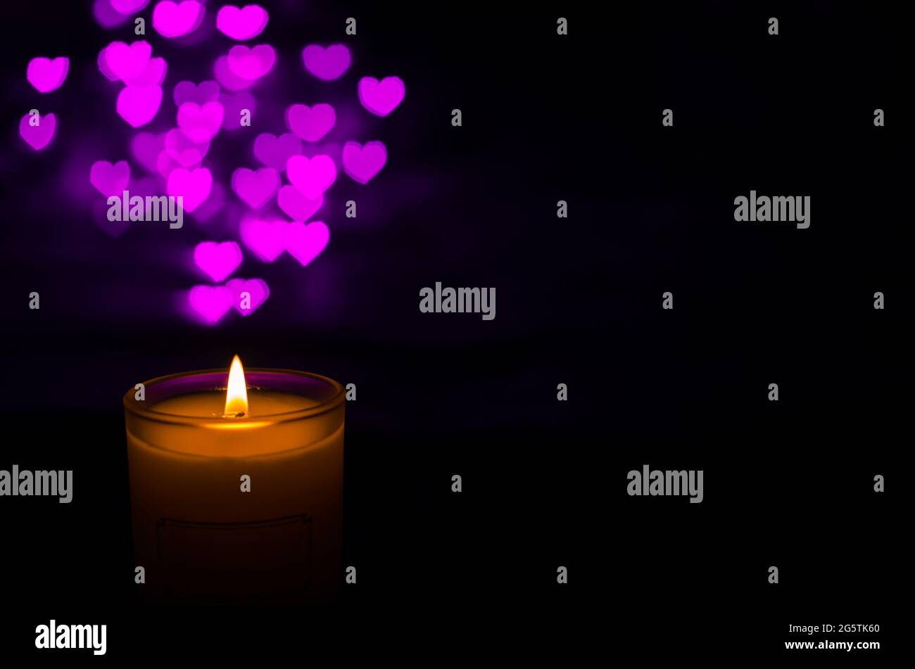Candela aromatica con fiamma e forma d'amore bokeh su sfondo scuro per ringraziamento e giorno di Natale. Foto Stock